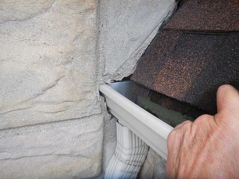 gutter discharging behind stone veneer siding found by the home inspector near evansville indiana